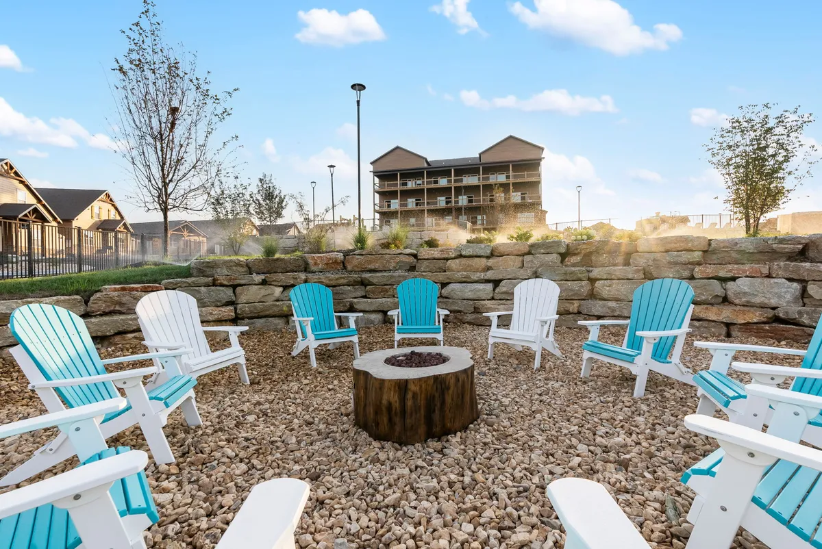 An inviting communal fire pit area surrounded by Adirondack chairs and lush greenery. The setting exudes warmth and togetherness, perfect for evening gatherings, roasting marshmallows, and sharing stories under the stars.
