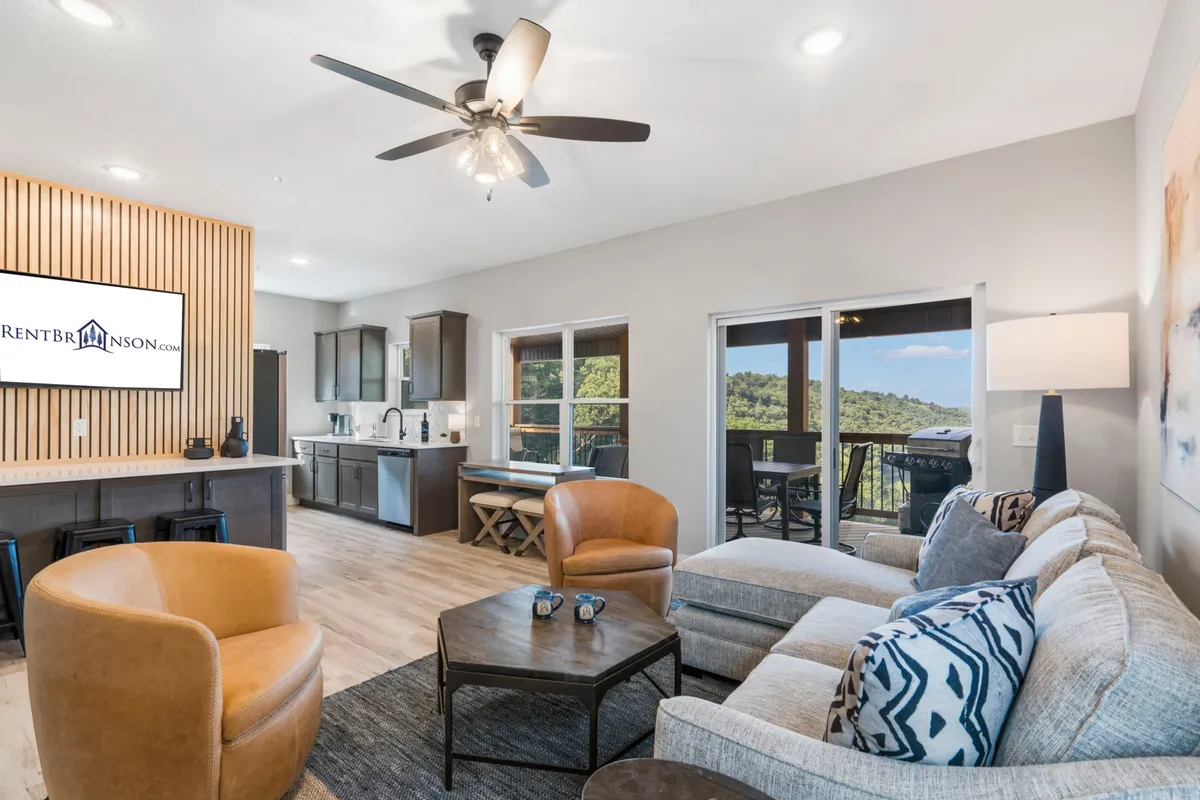 A welcoming seating area adjacent to a modern kitchen bar, featuring large windows with serene views and warm wooden accents. The layout fosters easy flow between kitchen and living spaces, ideal for socializing and soaking in the surrounding beauty.