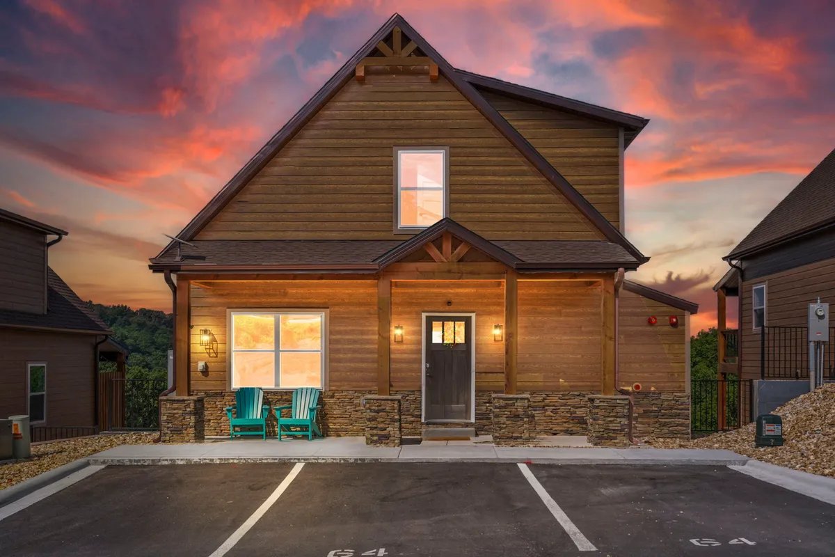 An inviting exterior shot featuring a wooden facade and a porch with chairs set against a vibrant sunset sky. The porch provides a welcoming space for socializing while offering views ideal for stargazing or sunset conversations.
