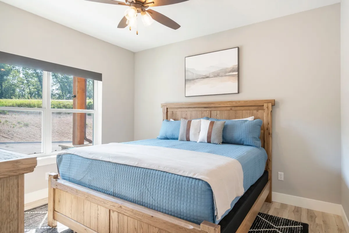 A tranquil bedroom with a large bed, ceiling fan, soft lighting, and a window allowing in natural light. The decor is simple and inviting, evoking a restful, comfortable atmosphere perfect for unwinding after a day of adventure.