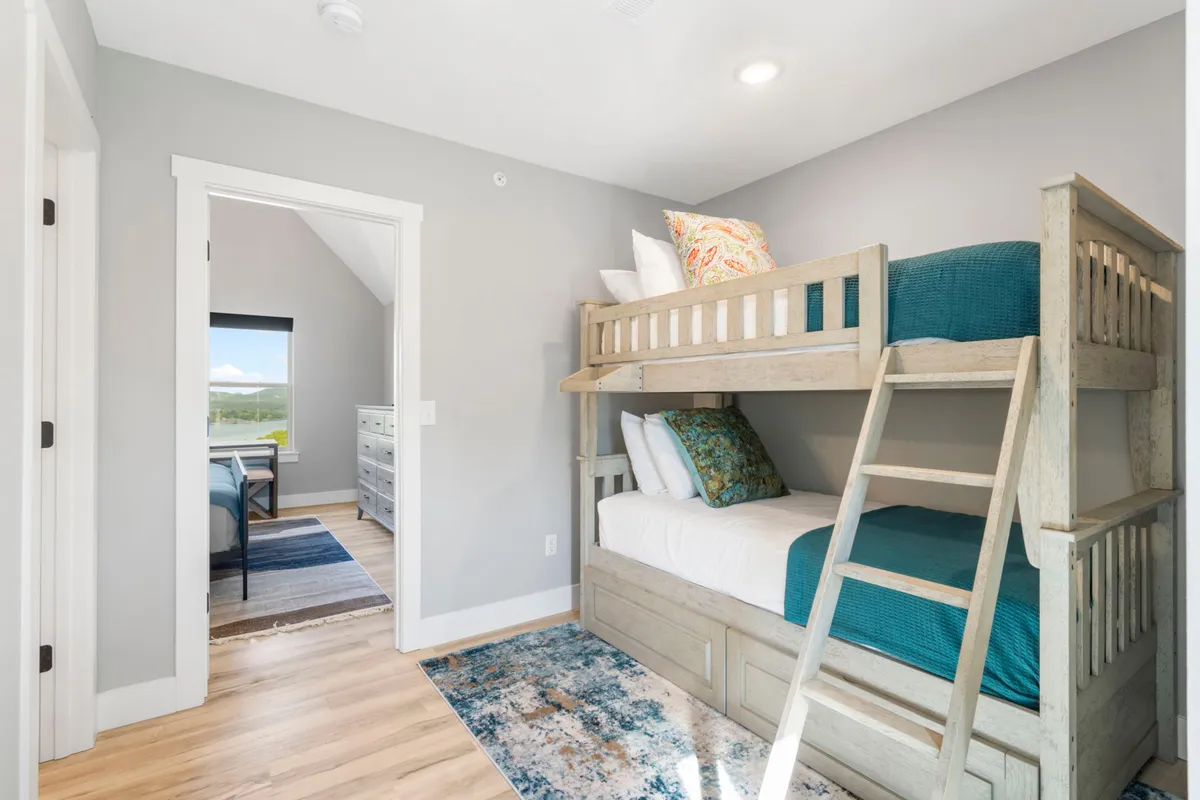 A cozy bunk bed setup with colorful pillows and a soft area rug, ideal for kids or families. The playful, welcoming vibe makes this space perfect for little dreamers and family bonding.